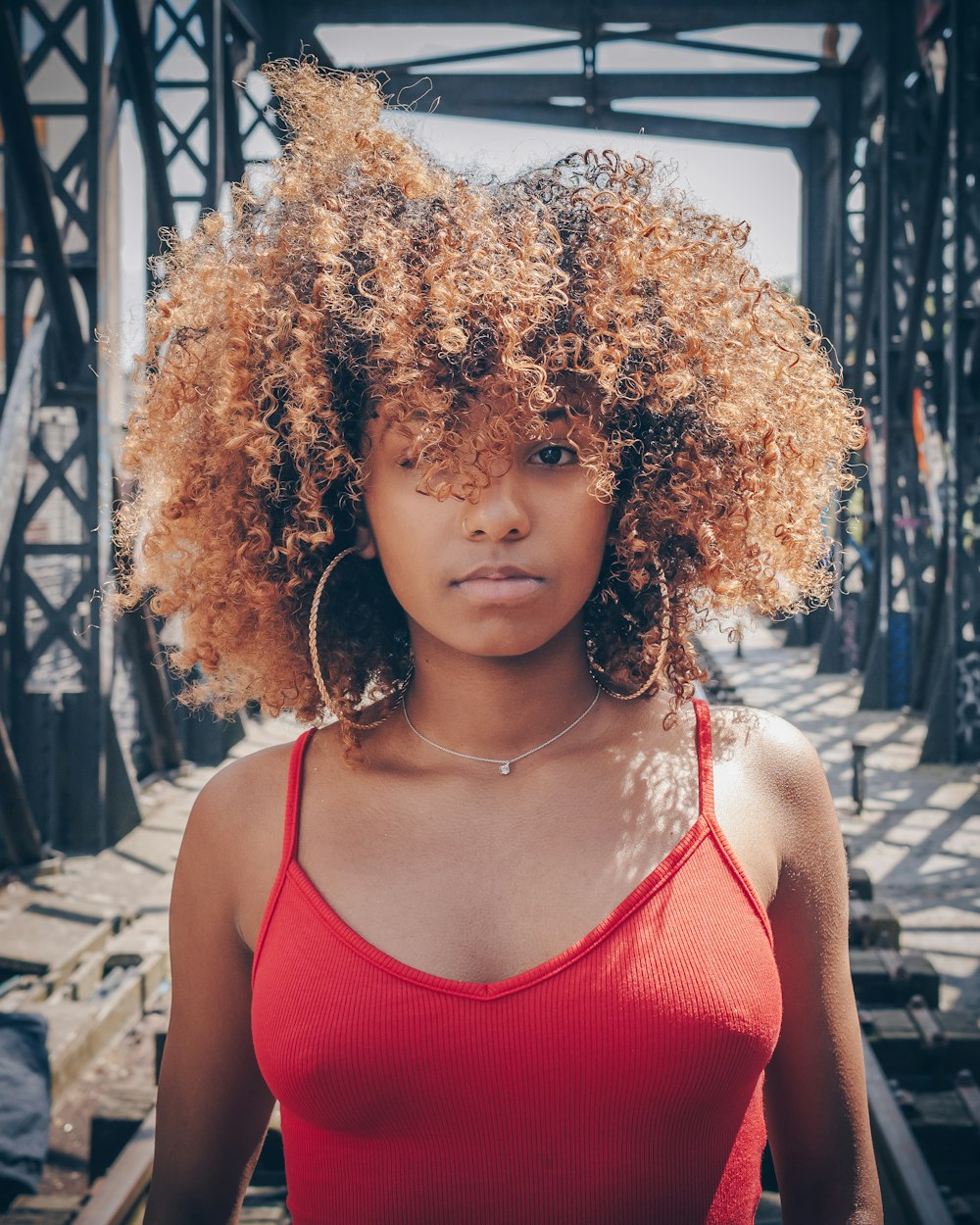 woman in red tank top with curly hair