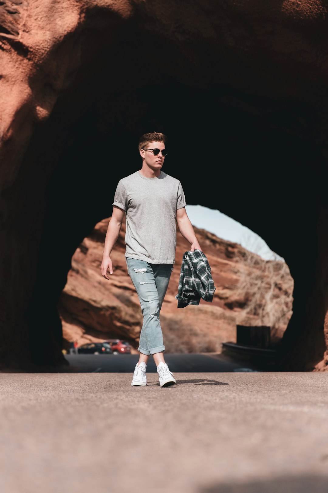 man in gray crew neck t-shirt and blue denim jeans standing near brown rock formation