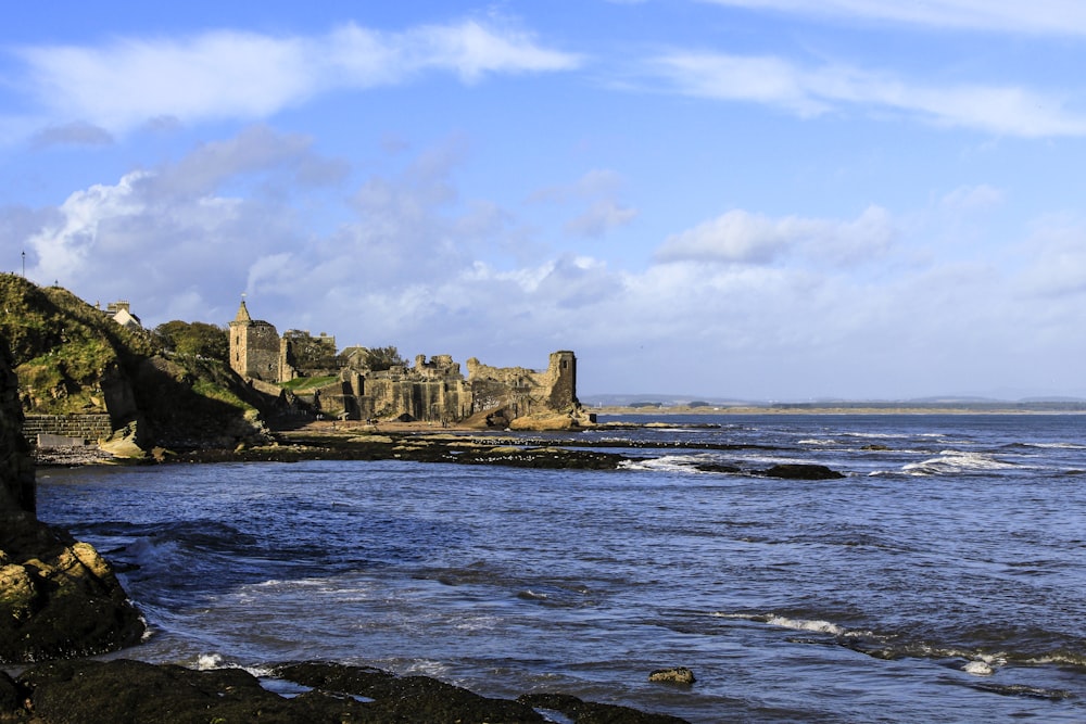 brown rock formation on sea under white clouds and blue sky during daytime