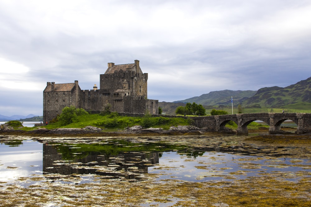 Castello di cemento marrone vicino allo specchio d'acqua sotto il cielo nuvoloso durante il giorno