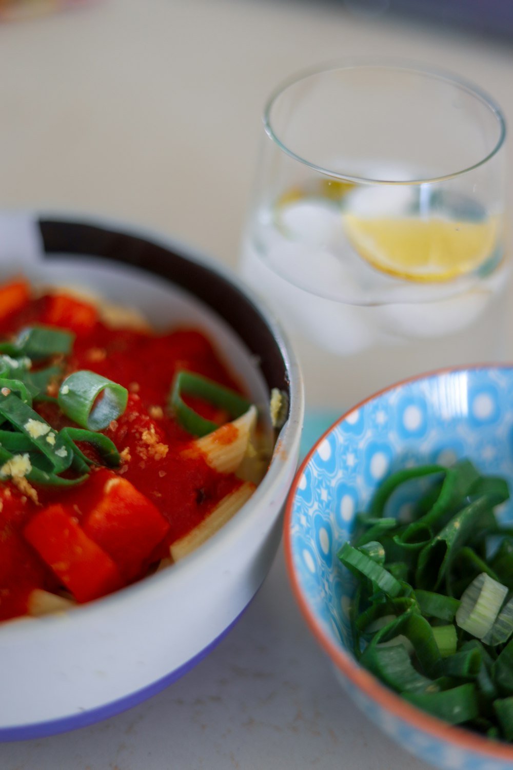 sliced tomato and green leaf vegetable in white ceramic bowl
