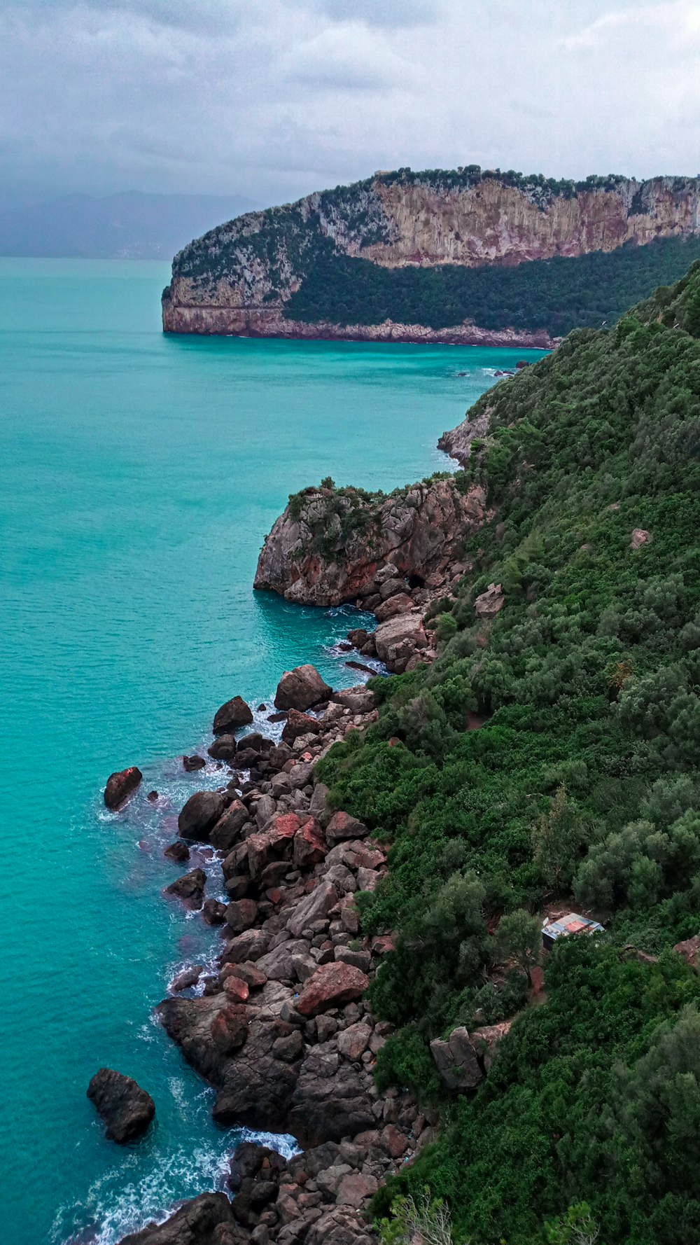 green and brown rock formation beside blue sea during daytime