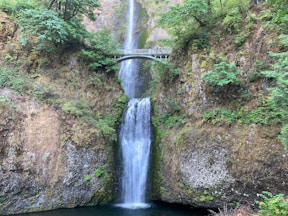 waterfalls between brown and green rock mountain during daytime
