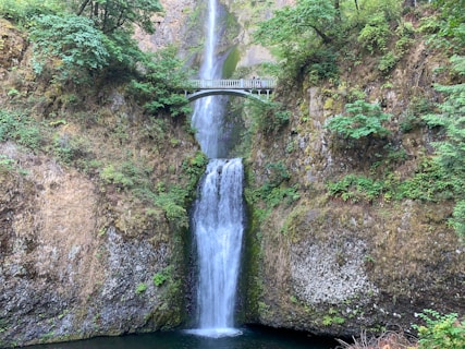 waterfalls between brown and green rock mountain during daytime