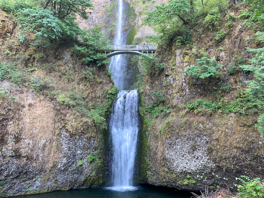 waterfalls between brown and green rock mountain during daytime