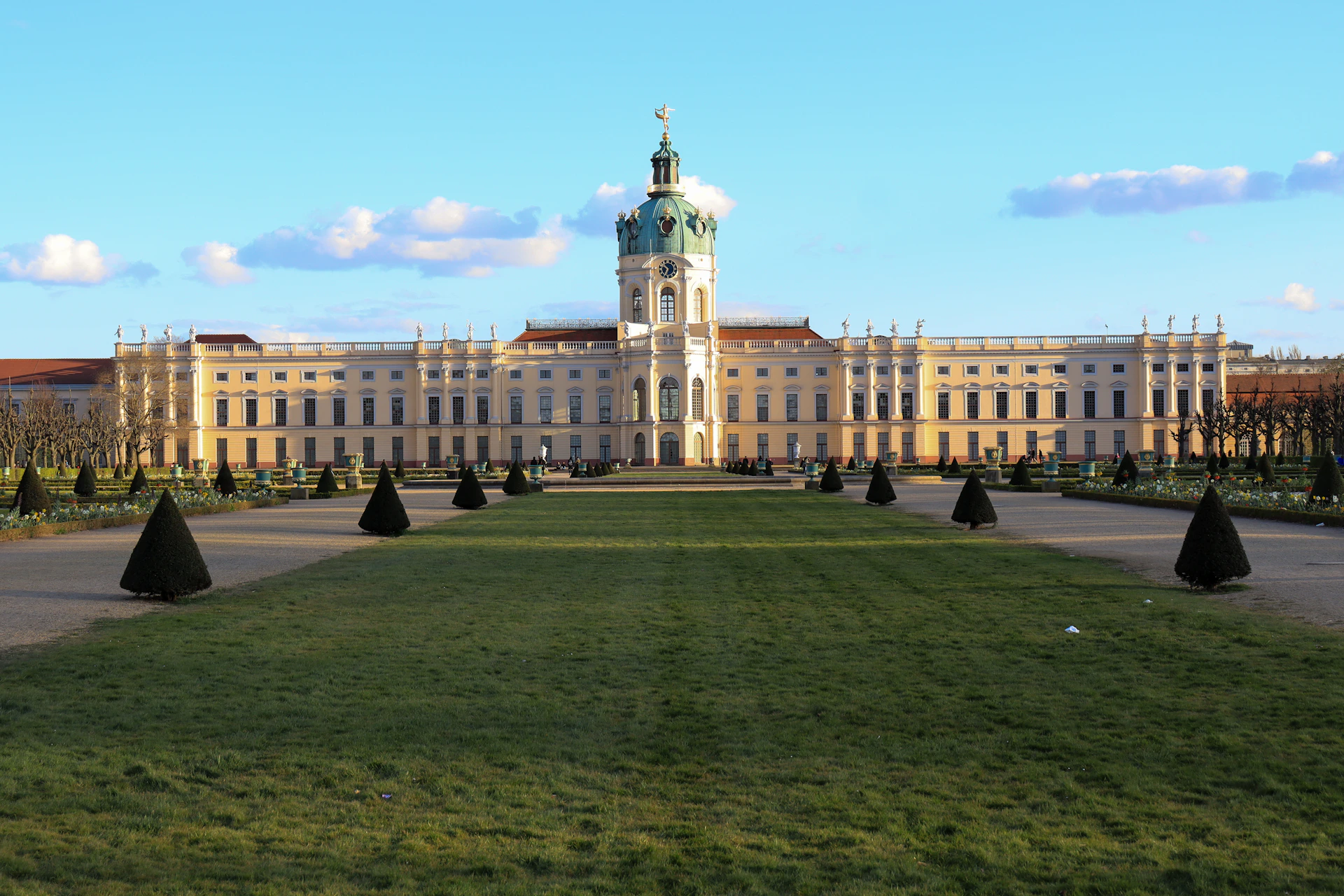 people walking on green grass field near white concrete building during daytime