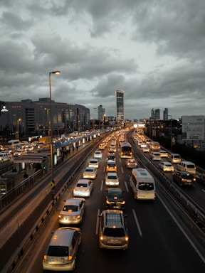 A close-up of hands typing on a laptop keyboard with a city highway visible in the background during dusk.