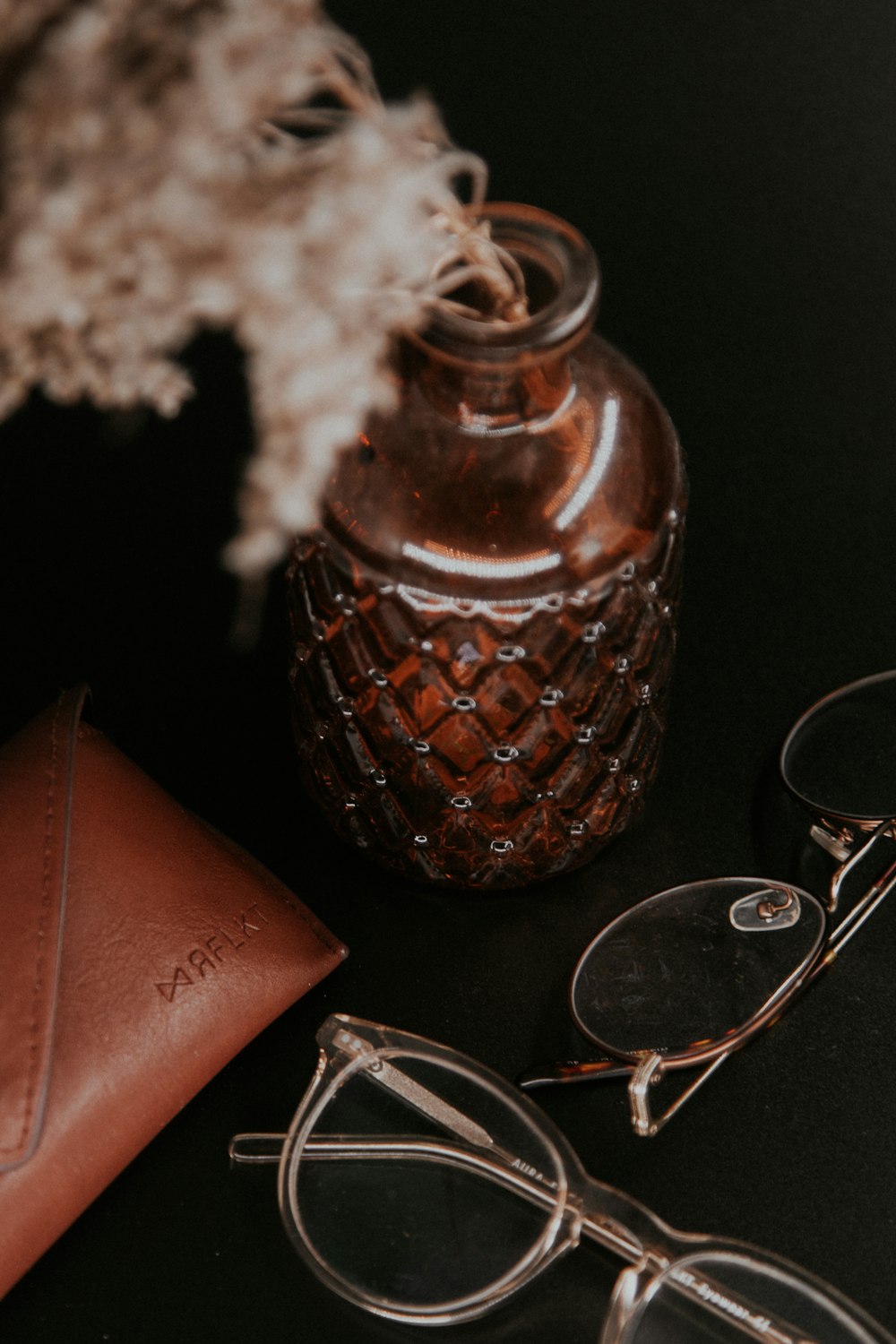 brown ceramic jar beside silver framed eyeglasses