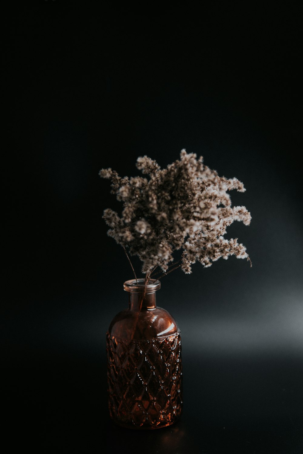 white flowers in brown glass bottle