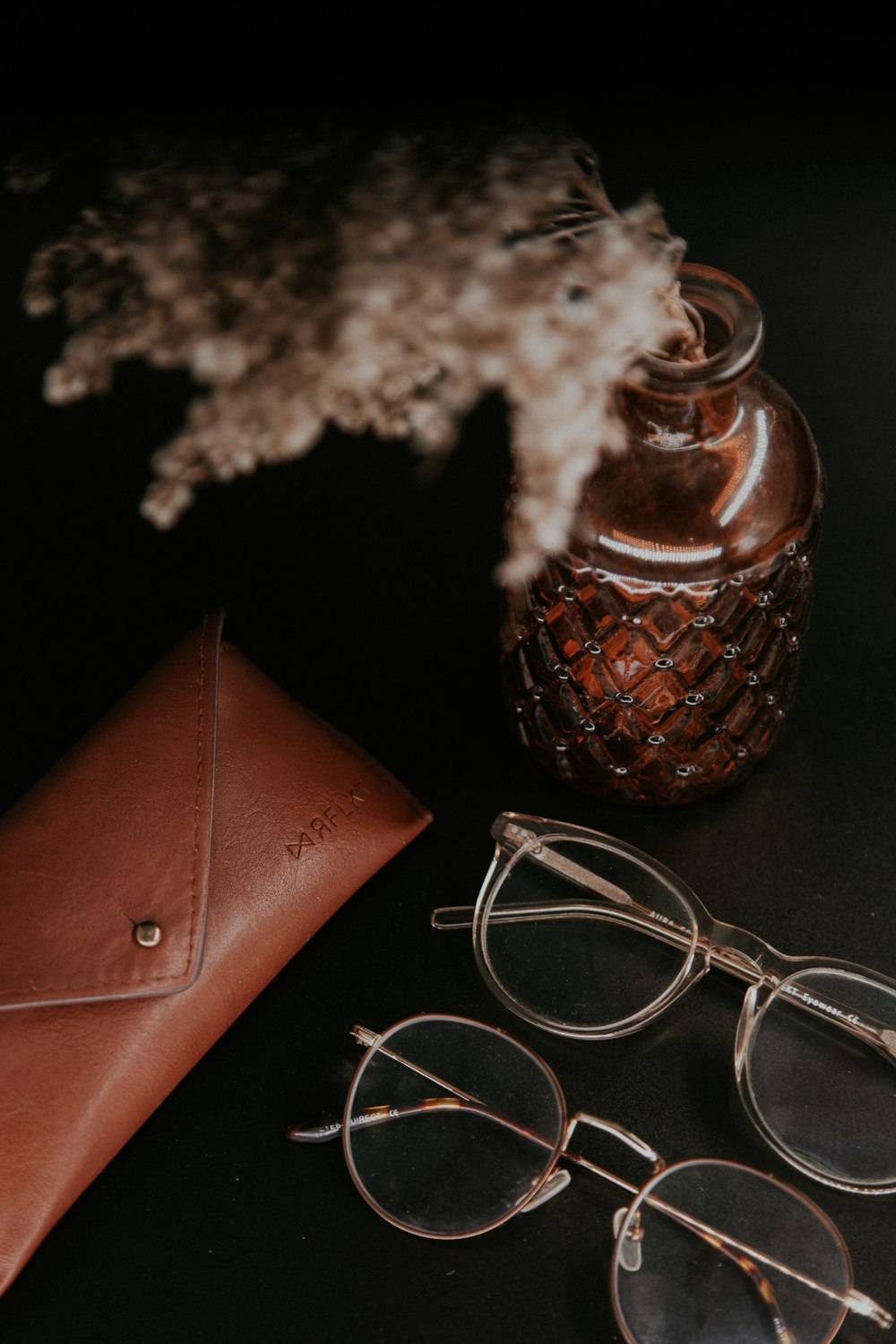 brown leather pouch beside white and black floral textile