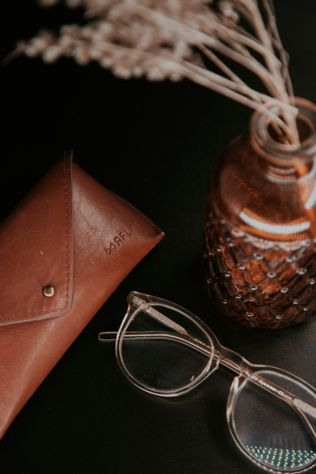 silver framed eyeglasses beside brown leather wallet