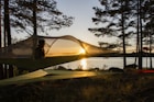 brown tent near body of water during sunset