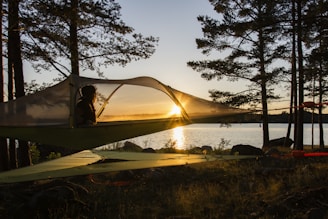 Image of a hiker happily relaxing inside a suspended float tent surrounded by trees.
