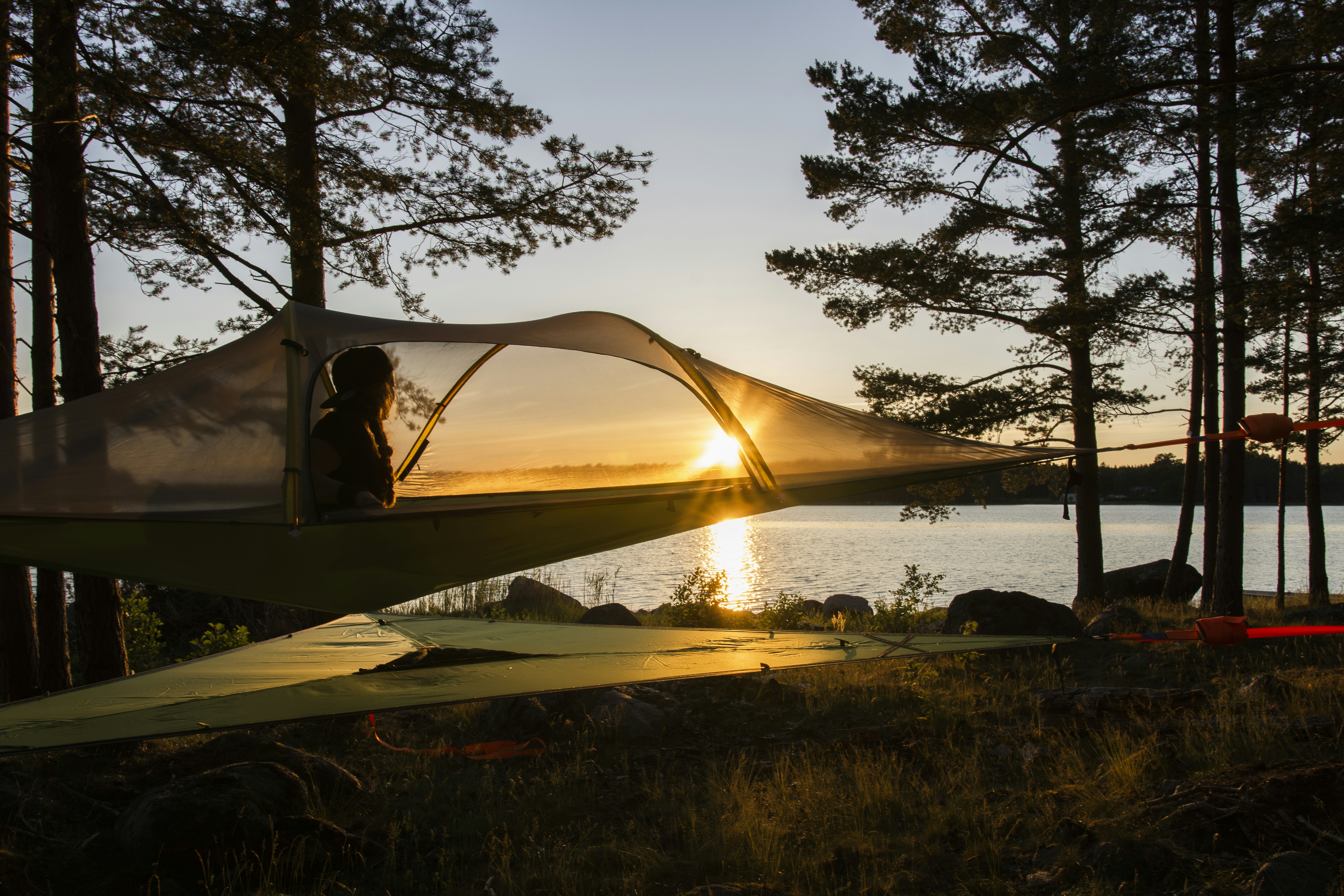 brown tent near body of water during sunset