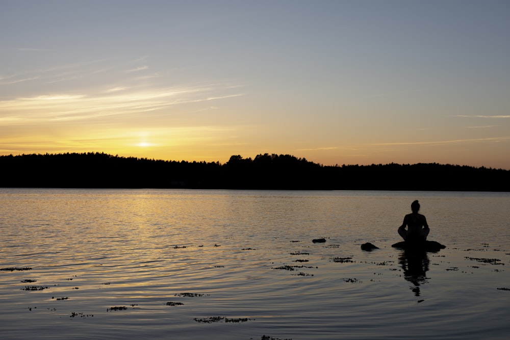 Silueta de la persona que monta en el barco en el agua durante la puesta del sol