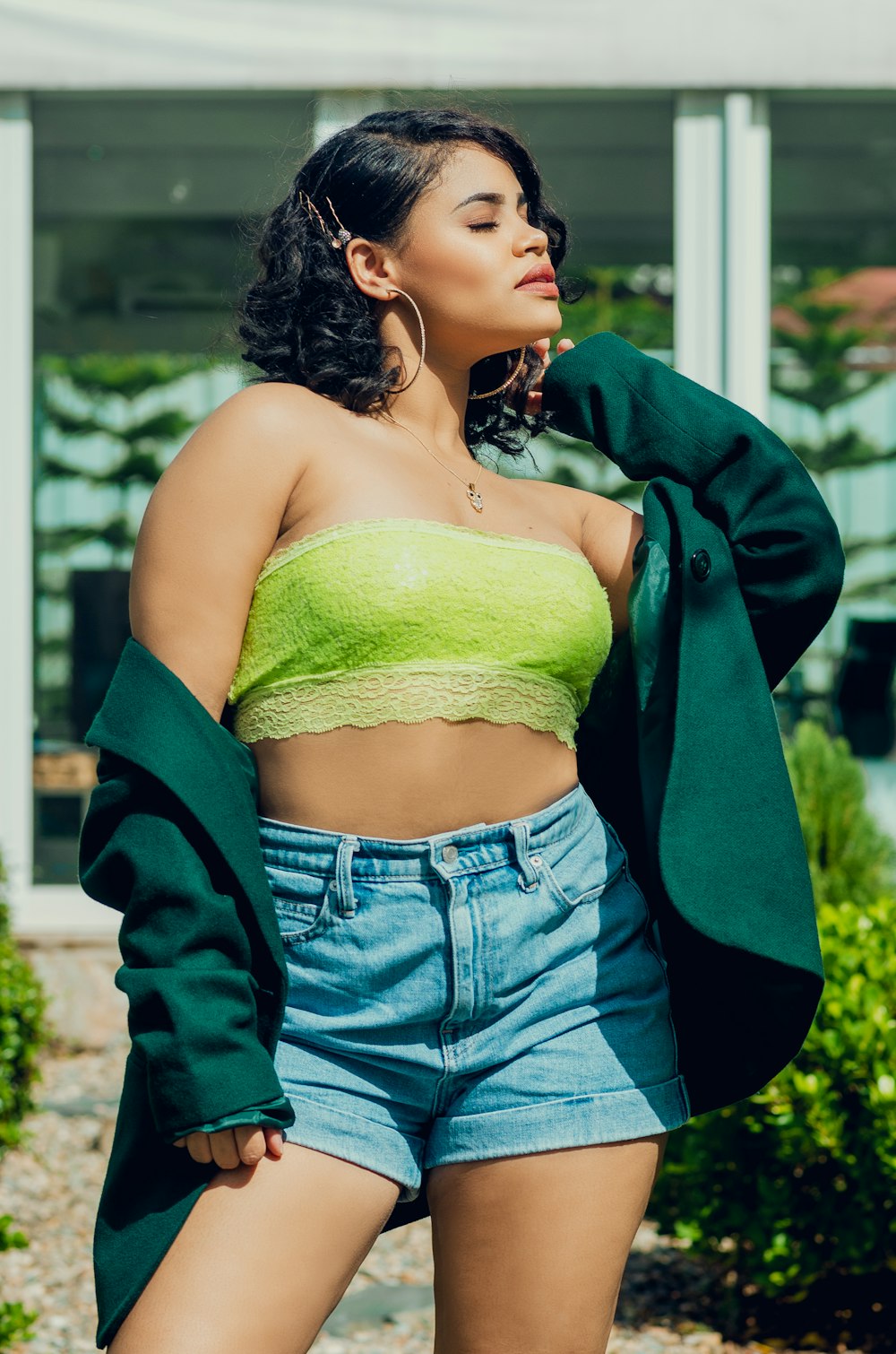 a woman wearing a green top and denim shorts