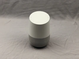 Minimalist smart home speaker with subtle blue light ring on a dark table