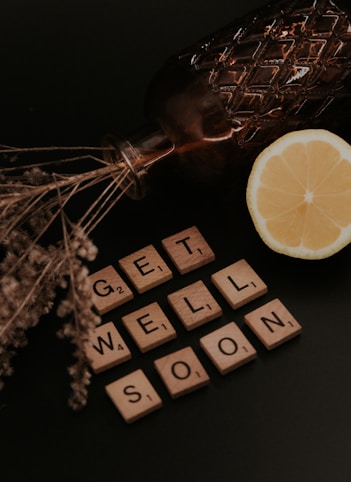sliced lemon on brown wooden desk. Scrable tiles read out: GET WELL SOON
