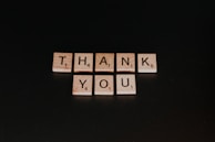 A collection of thank you stickers displayed on a rustic wooden board.