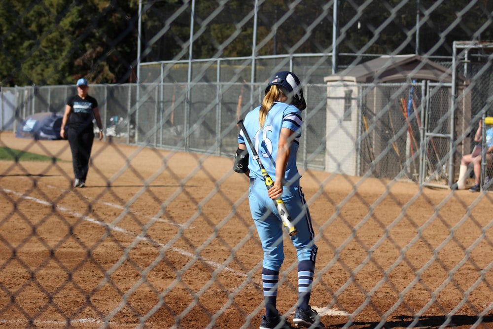 man in blue and white jersey shirt and pants standing on brown field during daytime