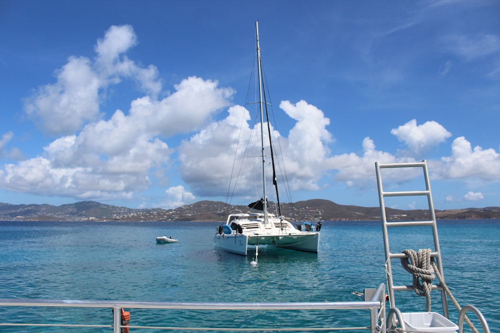 white sailboat on sea under blue sky and white clouds during daytime