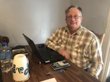 man in brown and white plaid button up shirt sitting beside brown wooden table with black