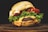 A juicy cheeseburger with a sesame seed bun, fresh green lettuce, and thick slices of tomato. Melted cheese oozes over the beef patty, enhancing its rich, savory appearance.