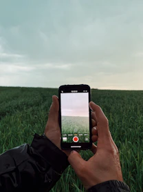 a person holding up a cell phone in a field