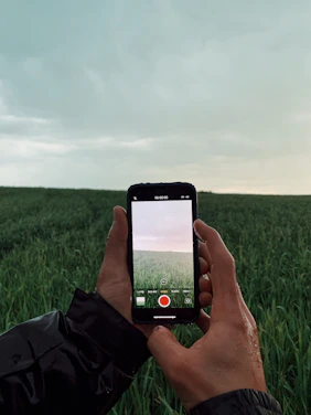 a person holding up a cell phone in a field