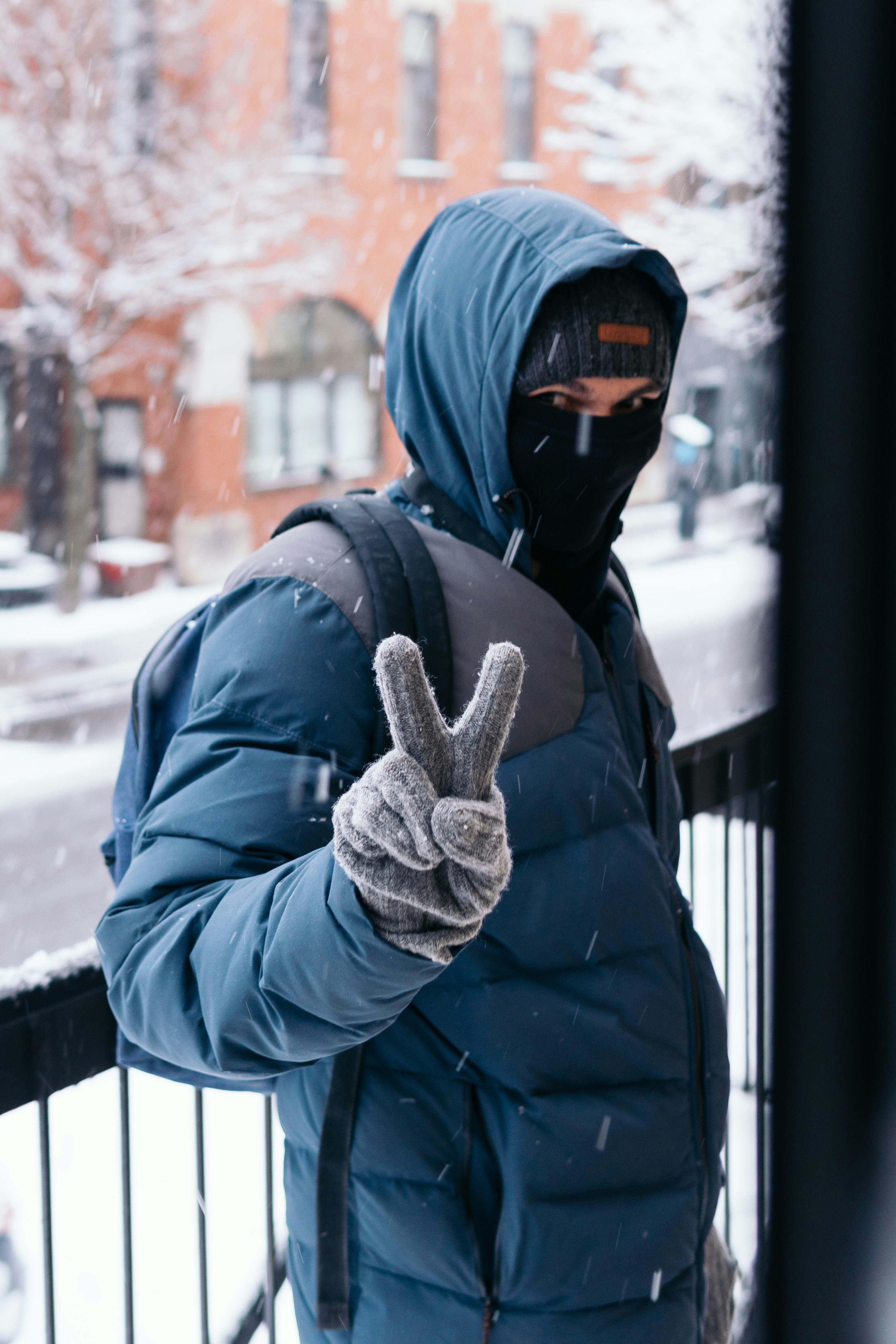 Person in schwarzer Jacke und schwarzer Strickmütze, die tagsüber auf schneebedecktem Boden steht