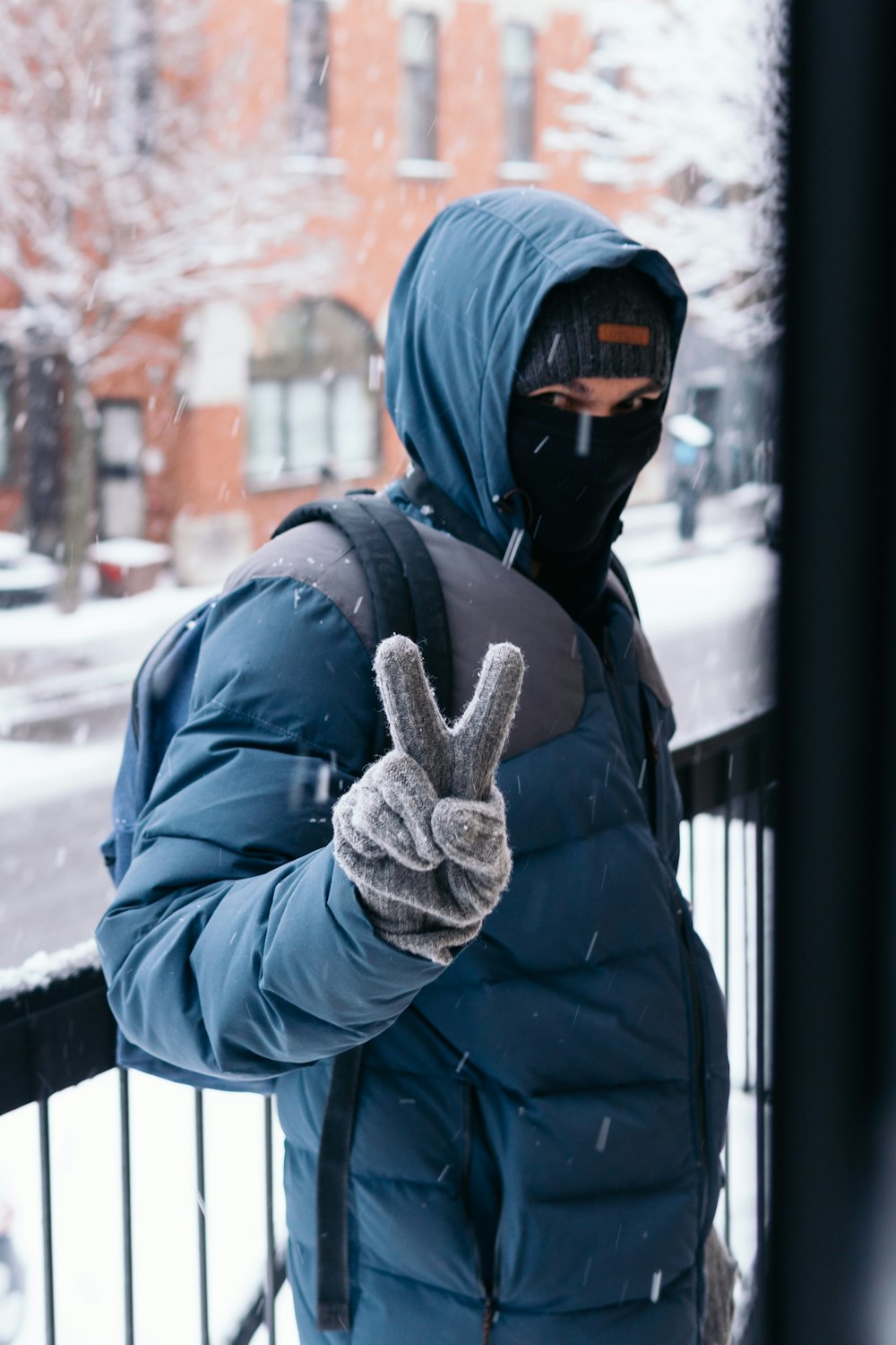 person in black jacket and black knit cap standing on snow covered ground during daytime