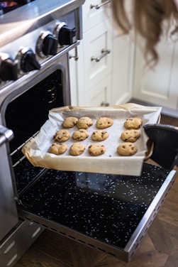 Danielle smiling in her kitchen surrounded by trays of freshly baked cookies.