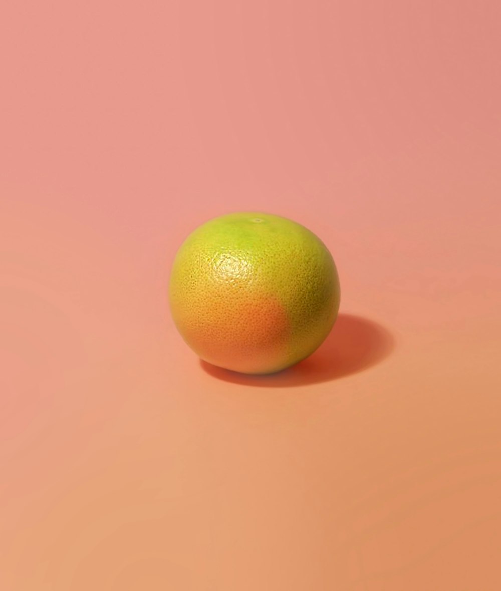 fruto redondo amarillo sobre superficie rosada