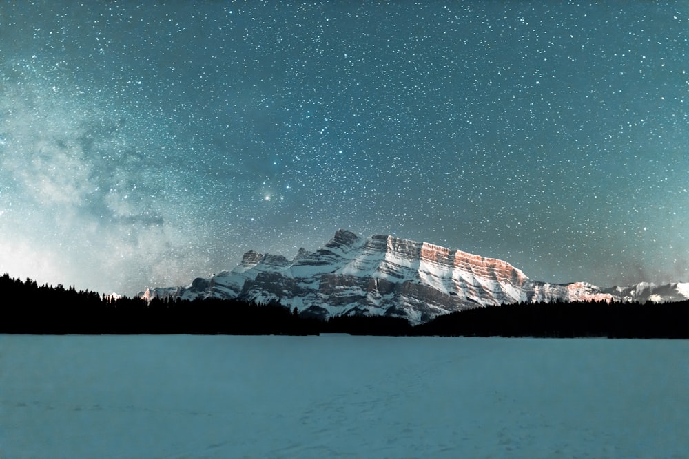 snow covered mountain under starry night