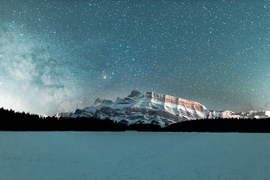 snow covered mountain under starry night in Two Jack Lake Canada