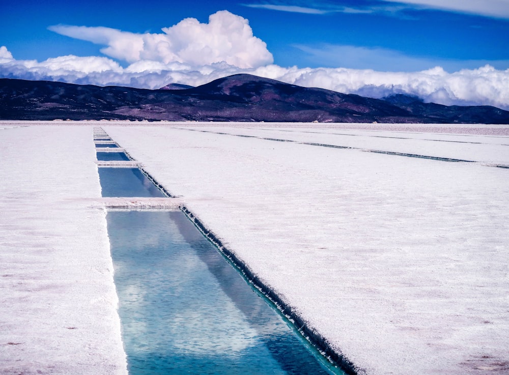 Suelo cubierto de nieve blanca cerca del cuerpo de agua durante el día