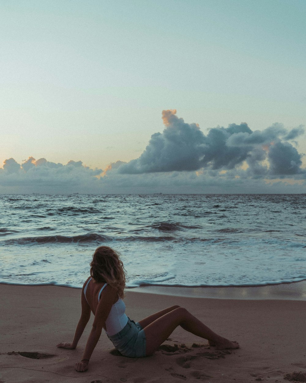 Mujer en bikini azul sentada en la orilla de la playa durante el día