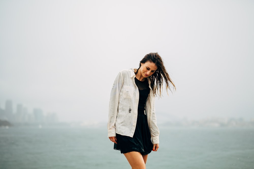 woman in white coat standing on beach during daytime