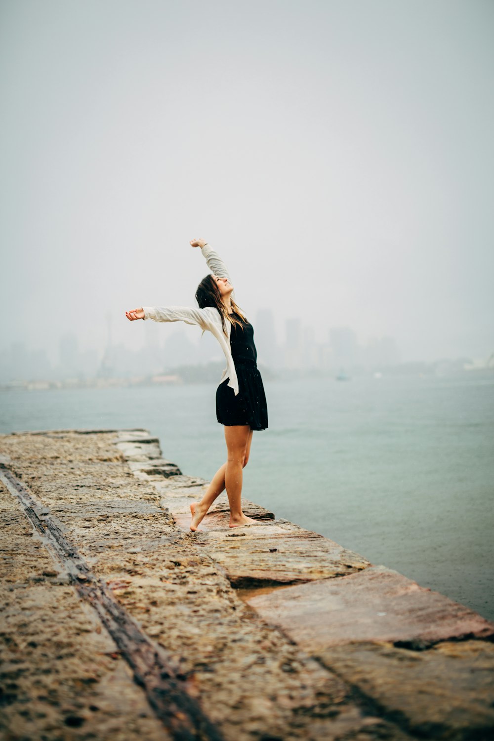 woman in black dress standing on concrete dock during daytime