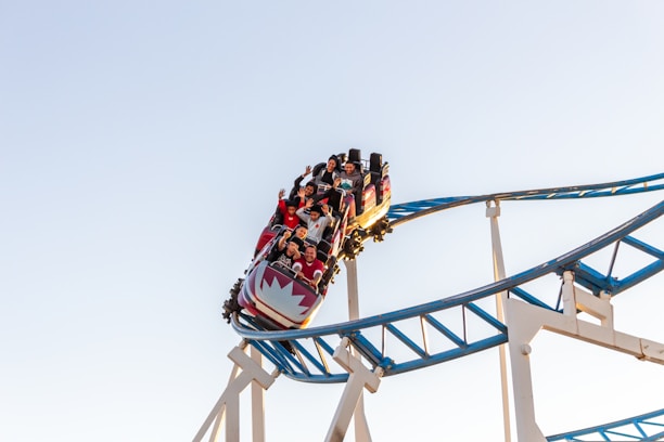 A joyful family enjoying a thrilling roller coaster ride under a bright blue sky.