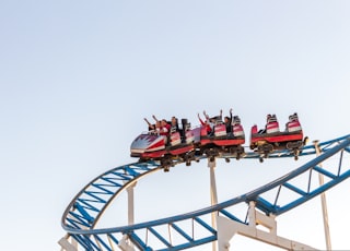 people riding red and white roller coaster during daytime