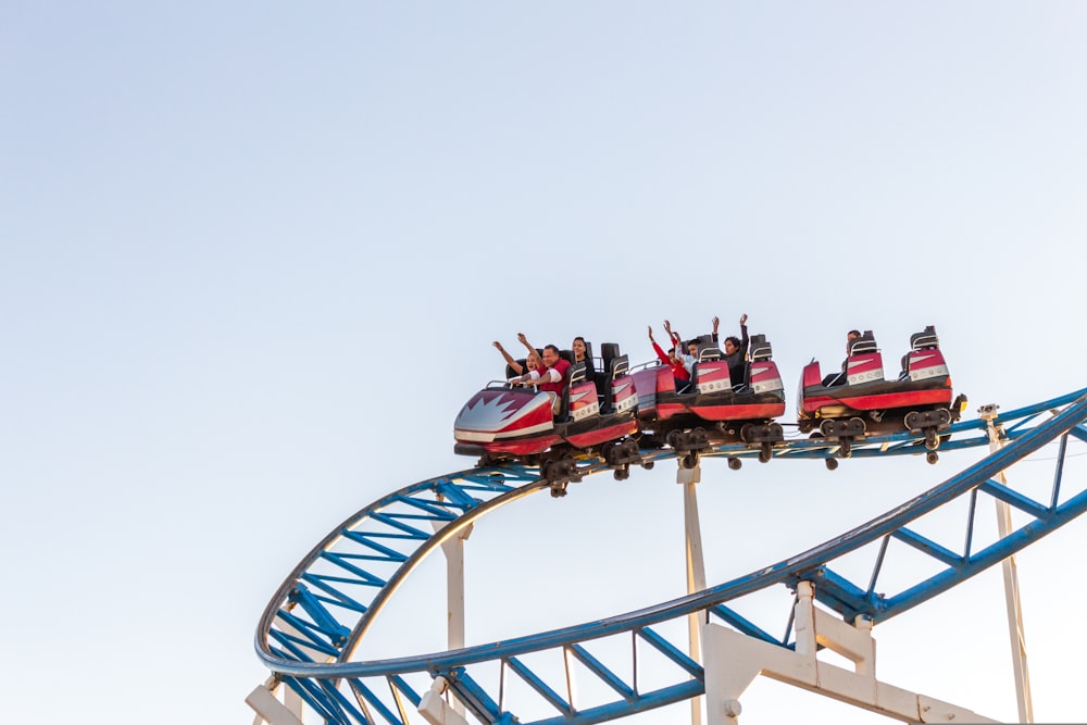 people riding red and white roller coaster during daytime