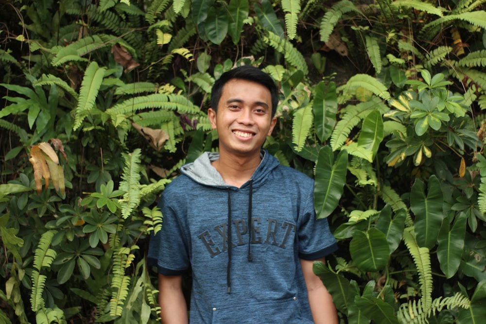 man in blue polo shirt standing near green plant