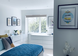 blue bed linen near white wooden framed glass window