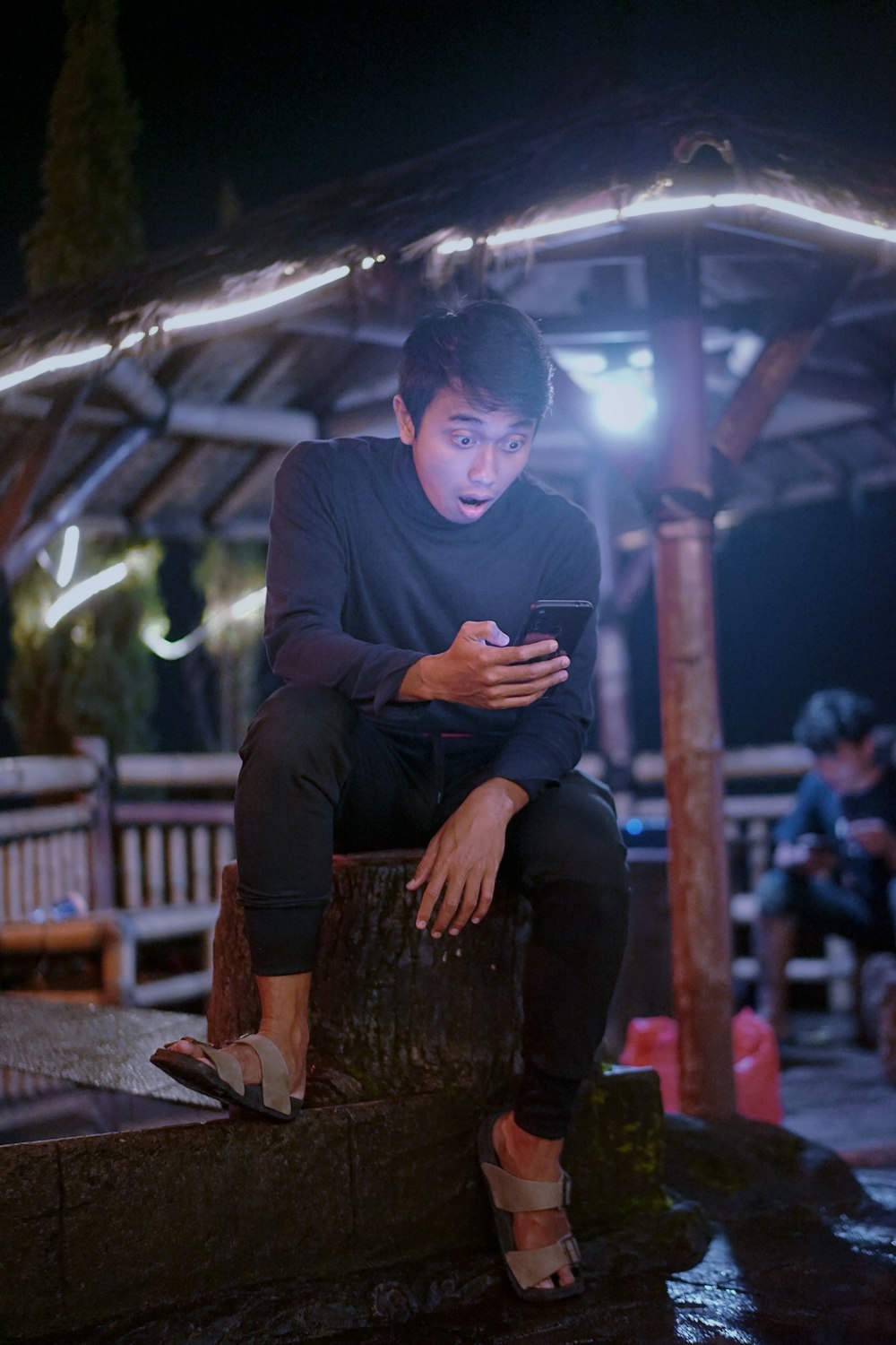 man in black long sleeve shirt sitting on brown wooden log