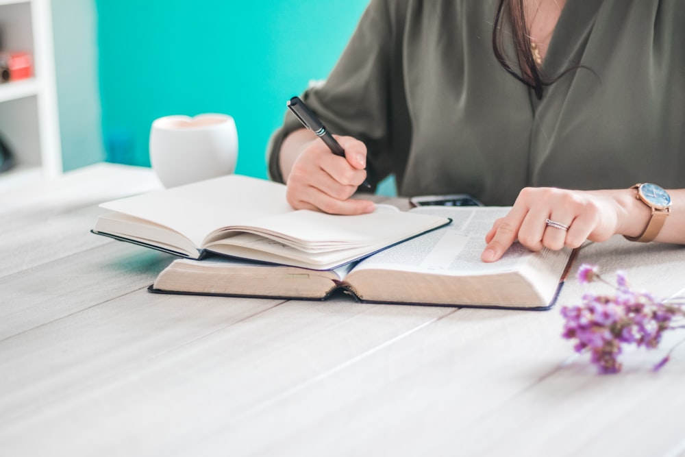 woman in gray robe writing on white paper