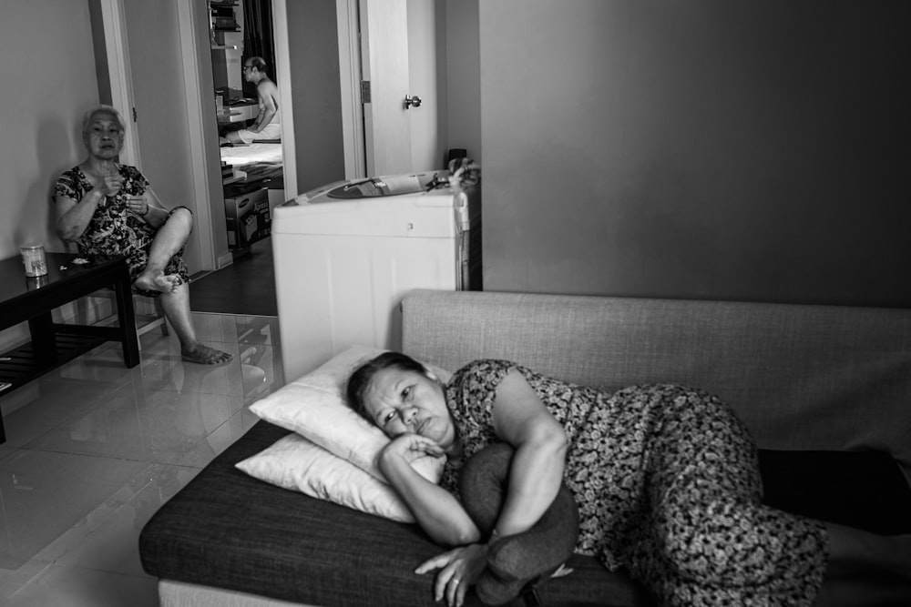 woman lying on bed in grayscale photography