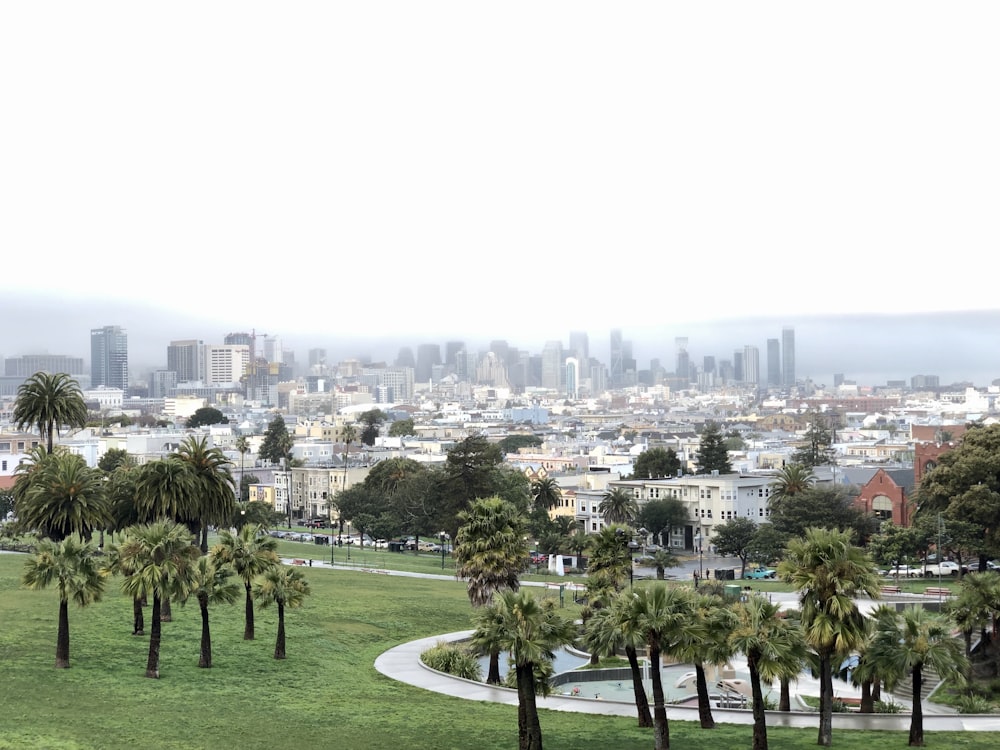 campo de grama verde perto de edifícios da cidade durante o dia