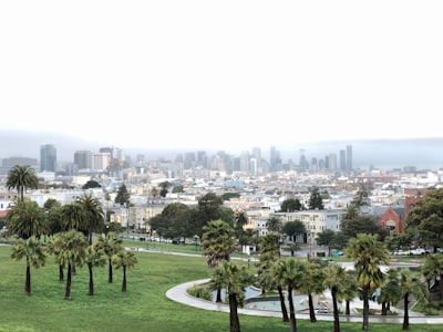 green grass field near city buildings during daytime