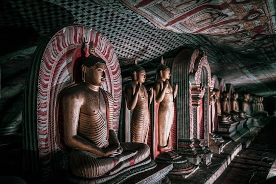 woman in brown dress sitting on floor in Dambulla cave temple Sri Lanka
